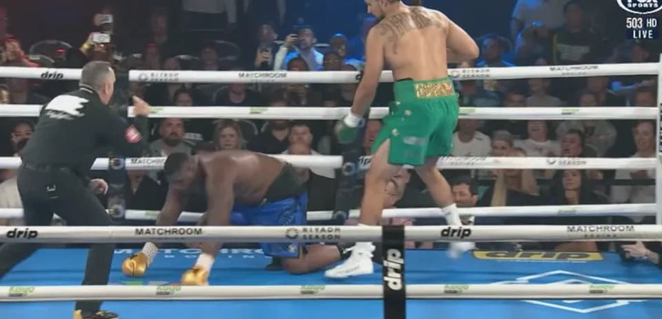 Boxer in green celebrates as opponent kneels down