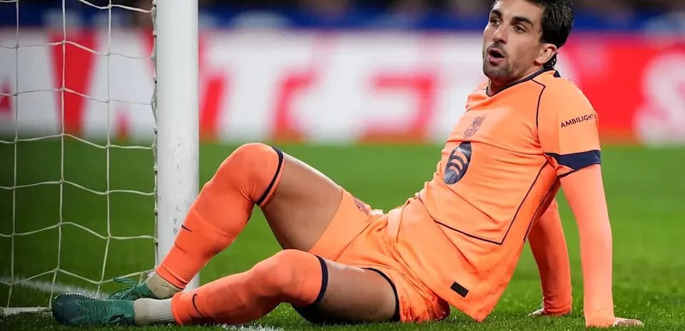 Goalkeeper sitting on pitch near goalpost