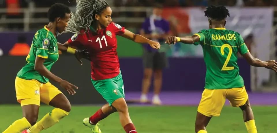 Moroccan player dribbling past two opponents during match