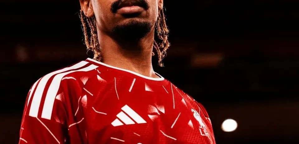 Futbolchi qizil forma kiygan holda turibdi