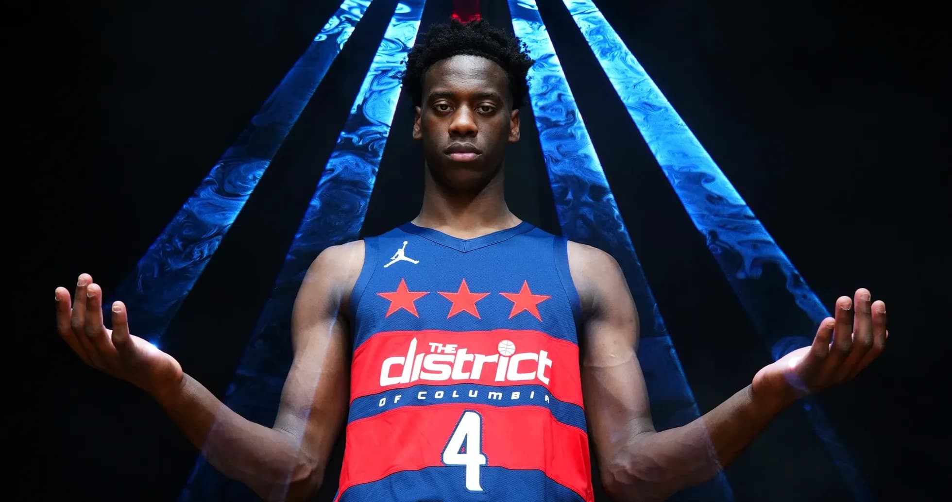 Basketball player posing in team jersey with arms raised