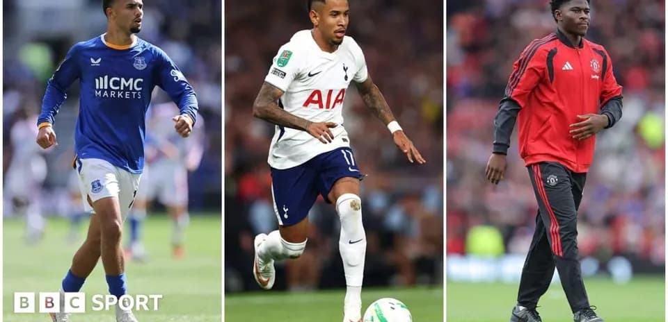 Three football players in team kits on the pitch