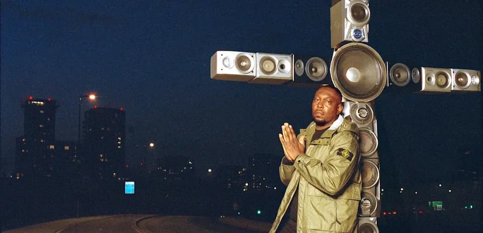Man posing beside large speaker installation at night
