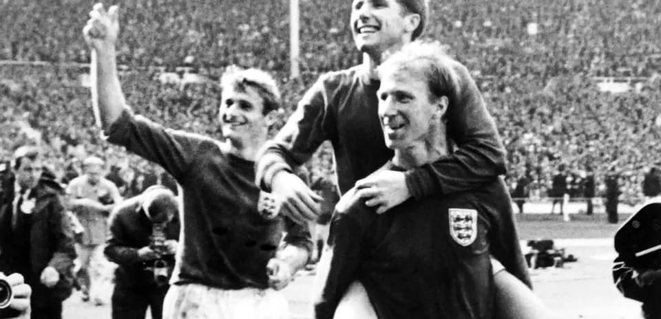 Three football players celebrating on the pitch
