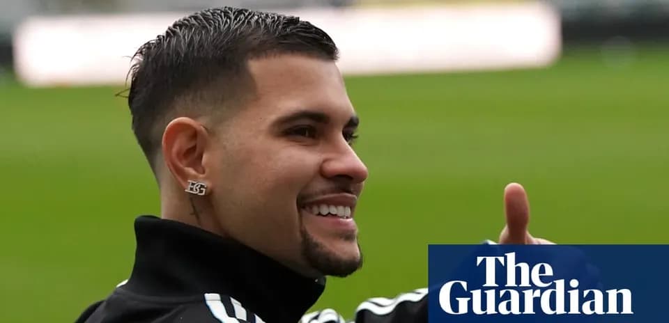 Futbolchi maydonda tabassum qilib qo'lini ko'tarayotgan