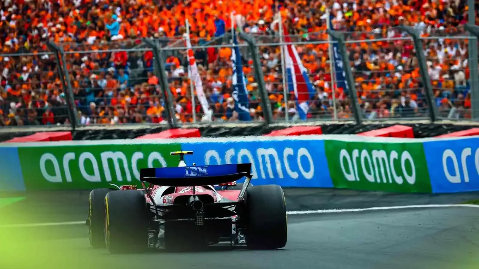 Formula 1 car racing past enthusiastic crowd