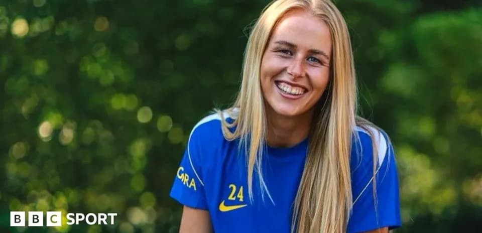 Futbolchi ko'k forma kiygan, tabassum qilayotgan