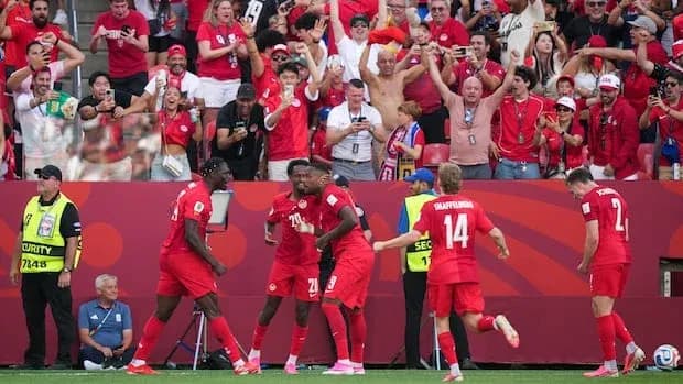 Players celebrating a goal with enthusiastic fans