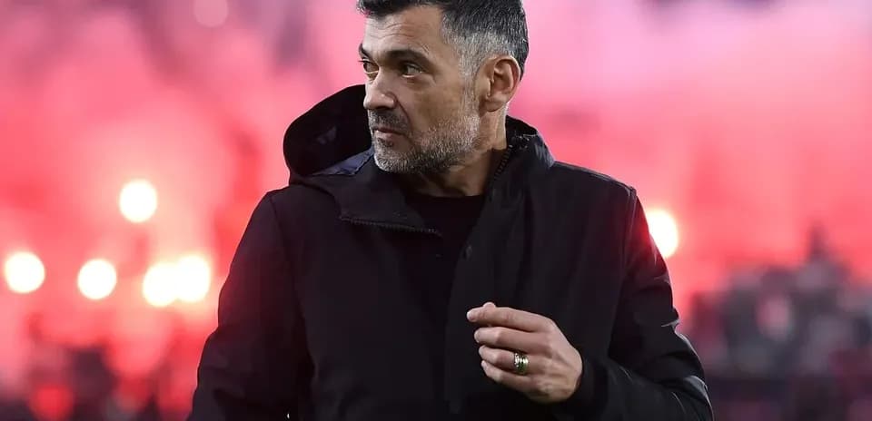 Coach observing match with flares in background