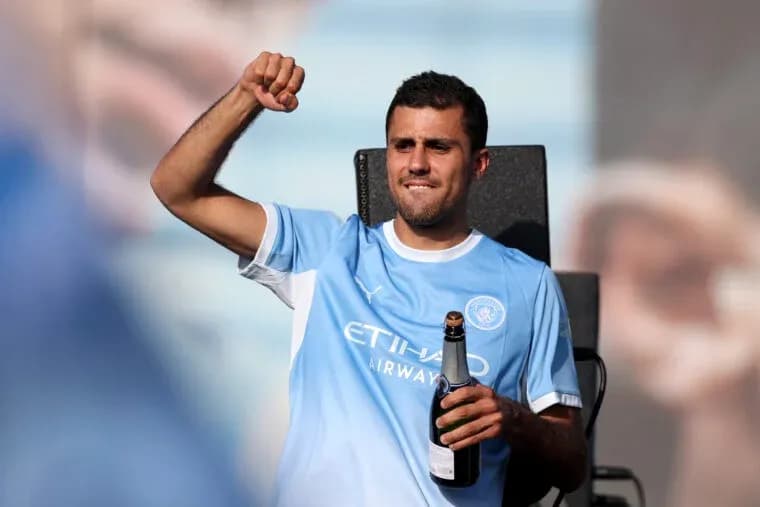 Futbolchi shampan bilan sahnada turib qo'lini ko'taradi Futbolchi shampan bilan sahnada turib qo'lini ko'taradi