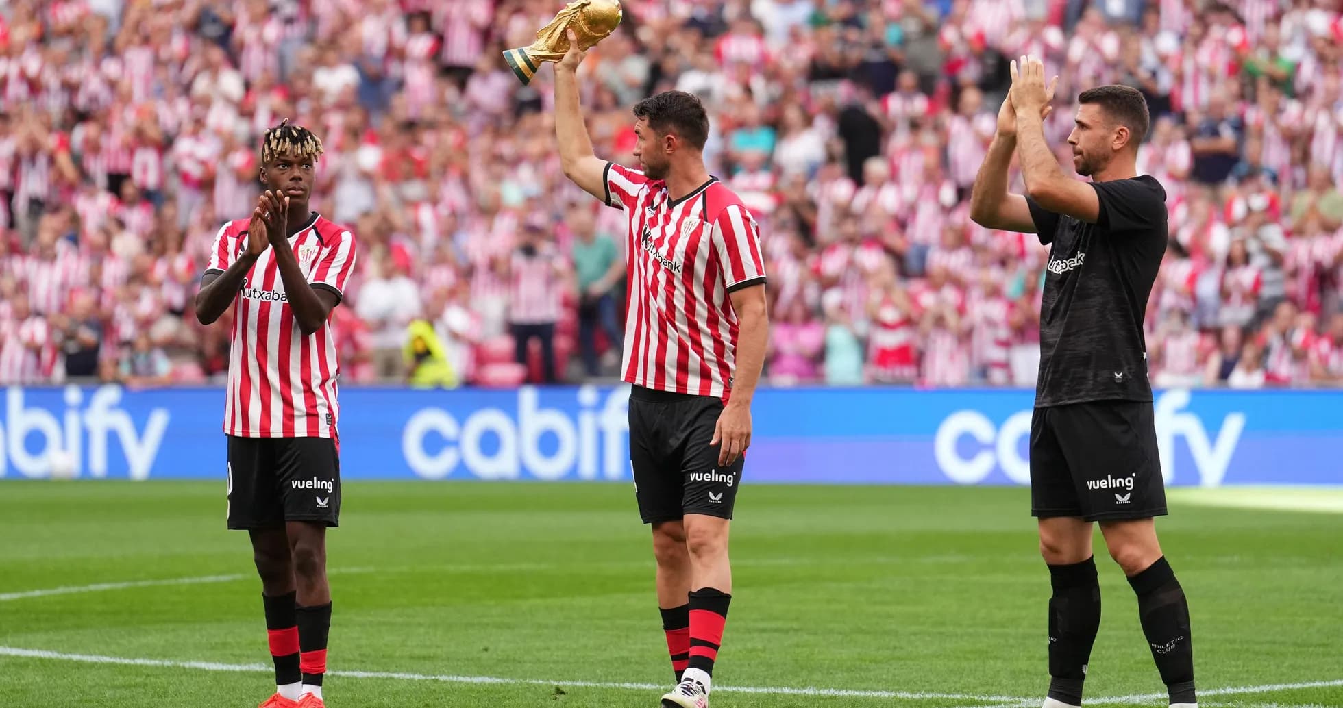 Athletic Bilbao players celebrating with trophy on pitch Athletic Bilbao players celebrating with trophy on pitch