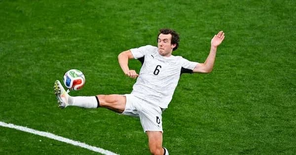 Futbolchi to'pni ushlash uchun yuqoriga sakrayapti Futbolchi to'pni ushlash uchun yuqoriga sakrayapti