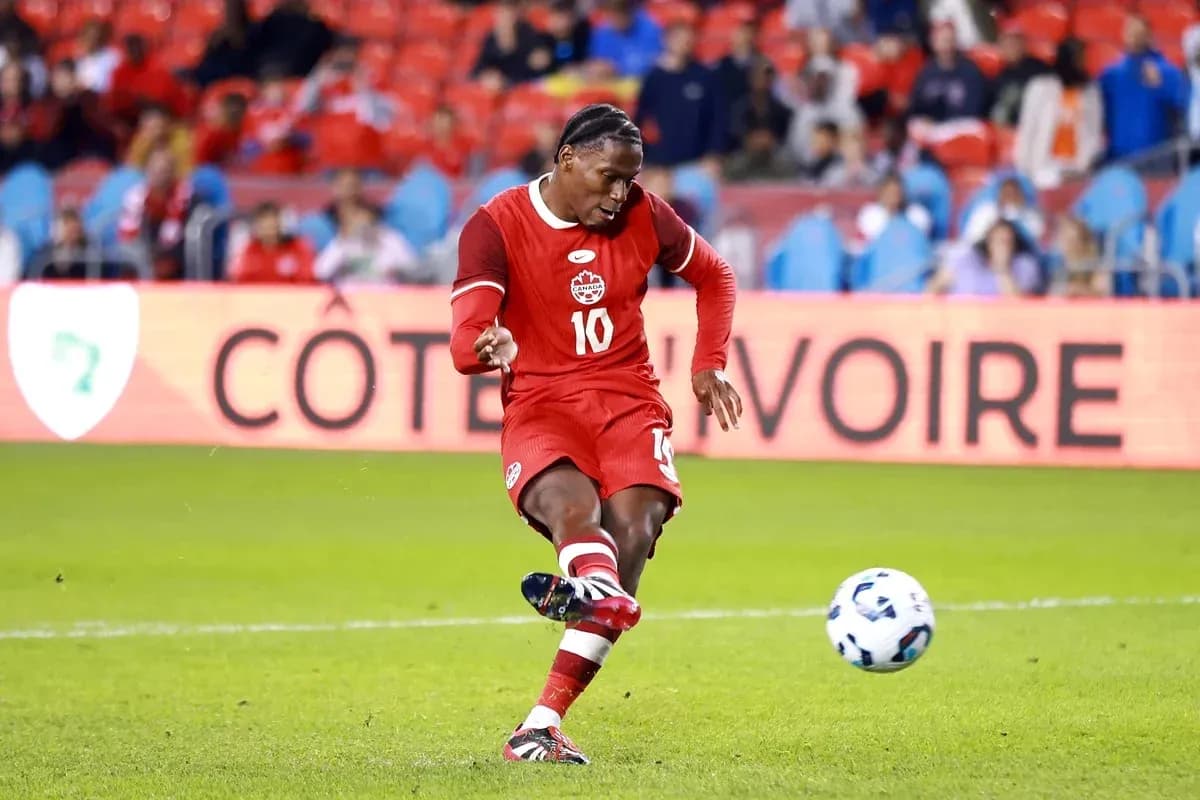 Player kicking ball during soccer match in red uniform Player kicking ball during soccer match in red uniform