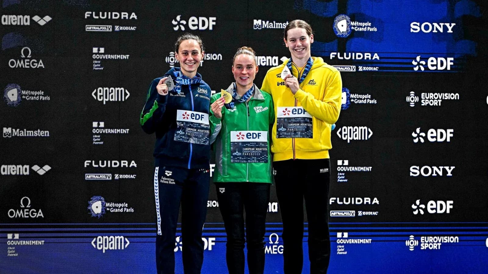 Three swimmers celebrating on podium with medals Three swimmers celebrating on podium with medals