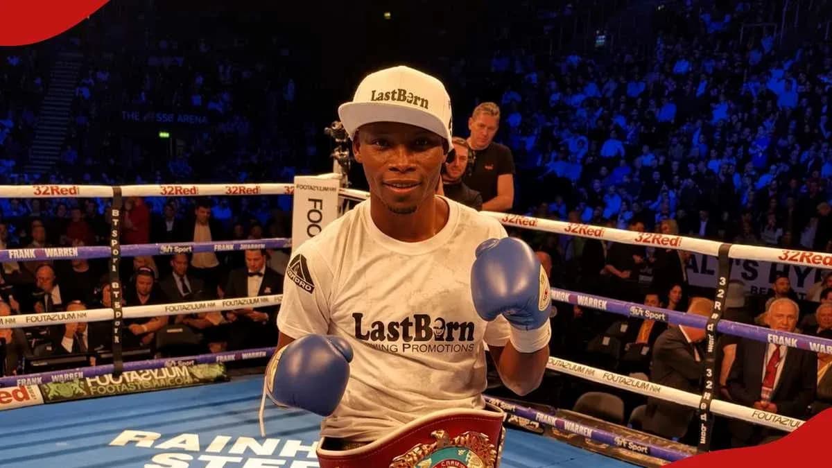 Boxer posing with gloves and championship belt in ring Boxer posing with gloves and championship belt in ring