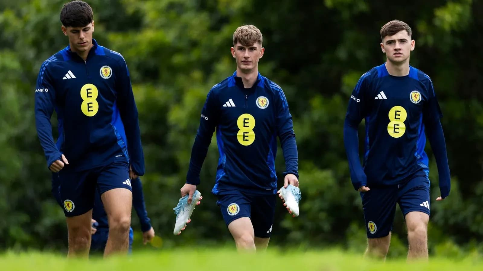 Three players walking in training gear on field Three players walking in training gear on field