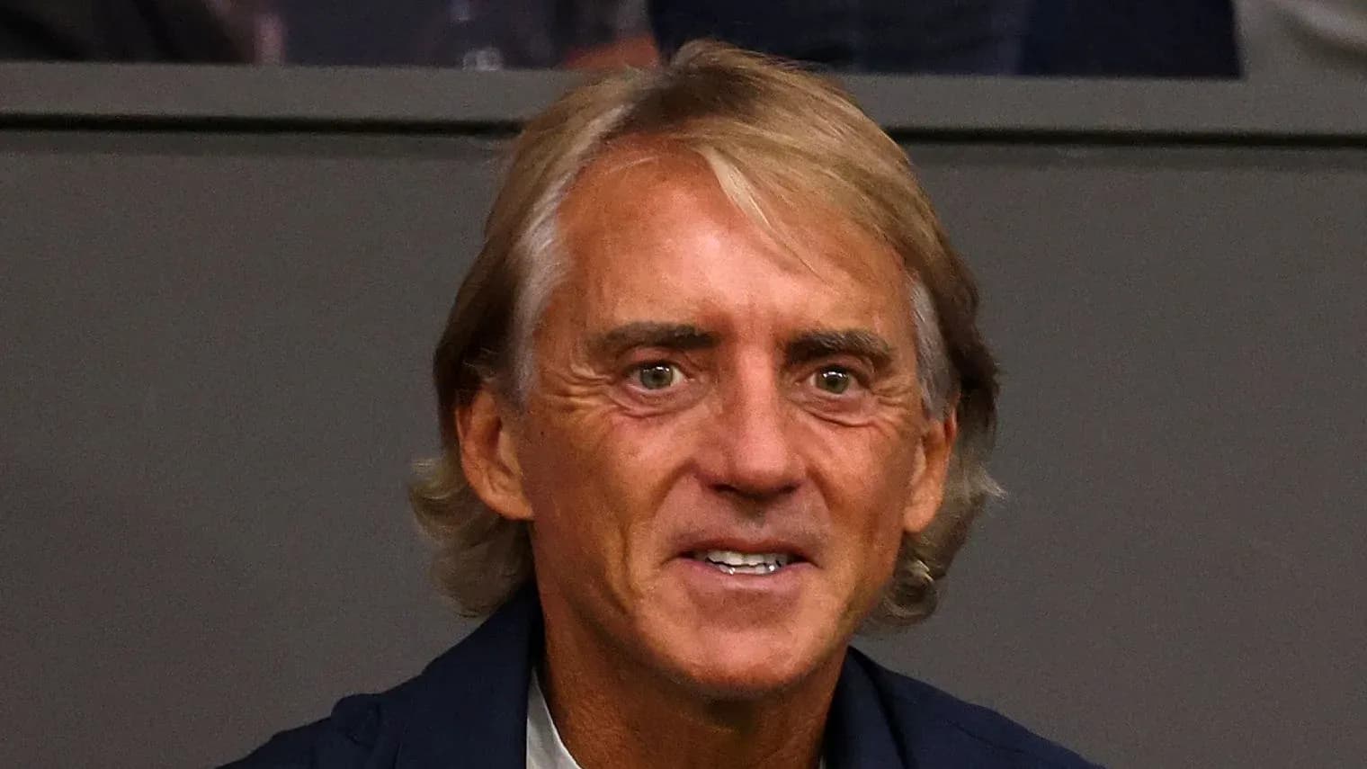 Shaggy-haired man smiling in a stadium setting Shaggy-haired man smiling in a stadium setting
