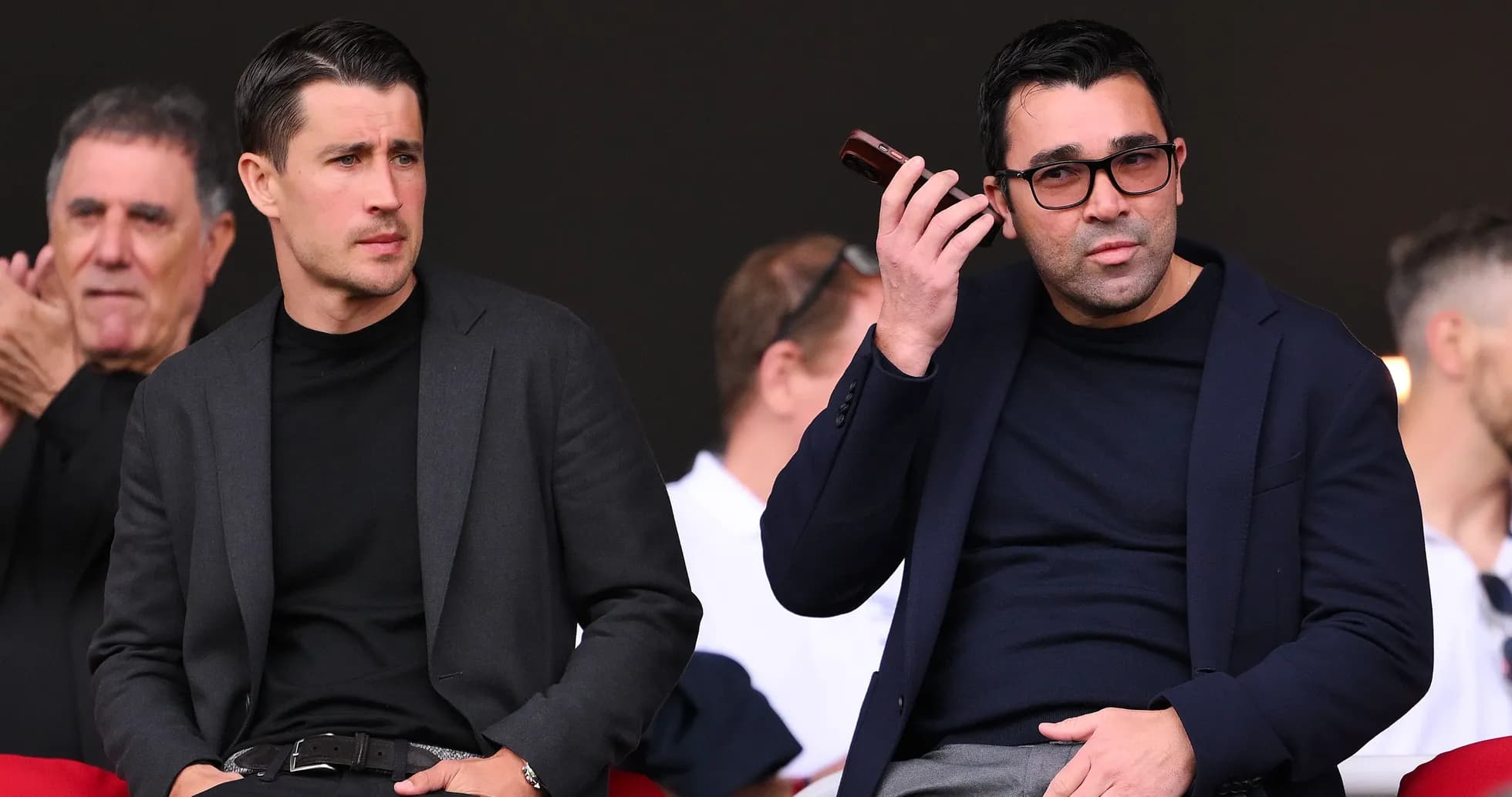 Two men seated in stands during event Two men seated in stands during event