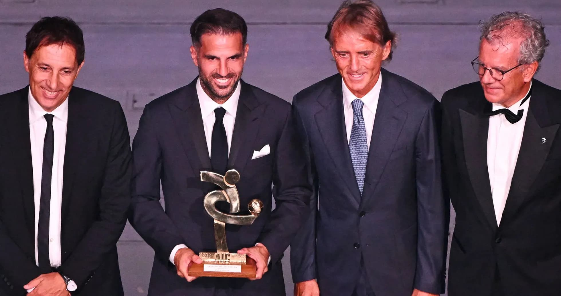 Four men posing with a trophy at an event Four men posing with a trophy at an event