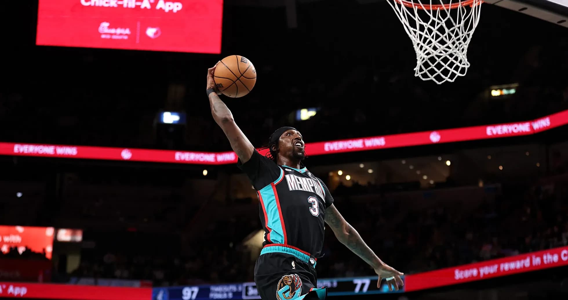 O'yinchi slam dunk qilmoqda, stadionda banner ko'rinmoqda O'yinchi slam dunk qilmoqda, stadionda banner ko'rinmoqda