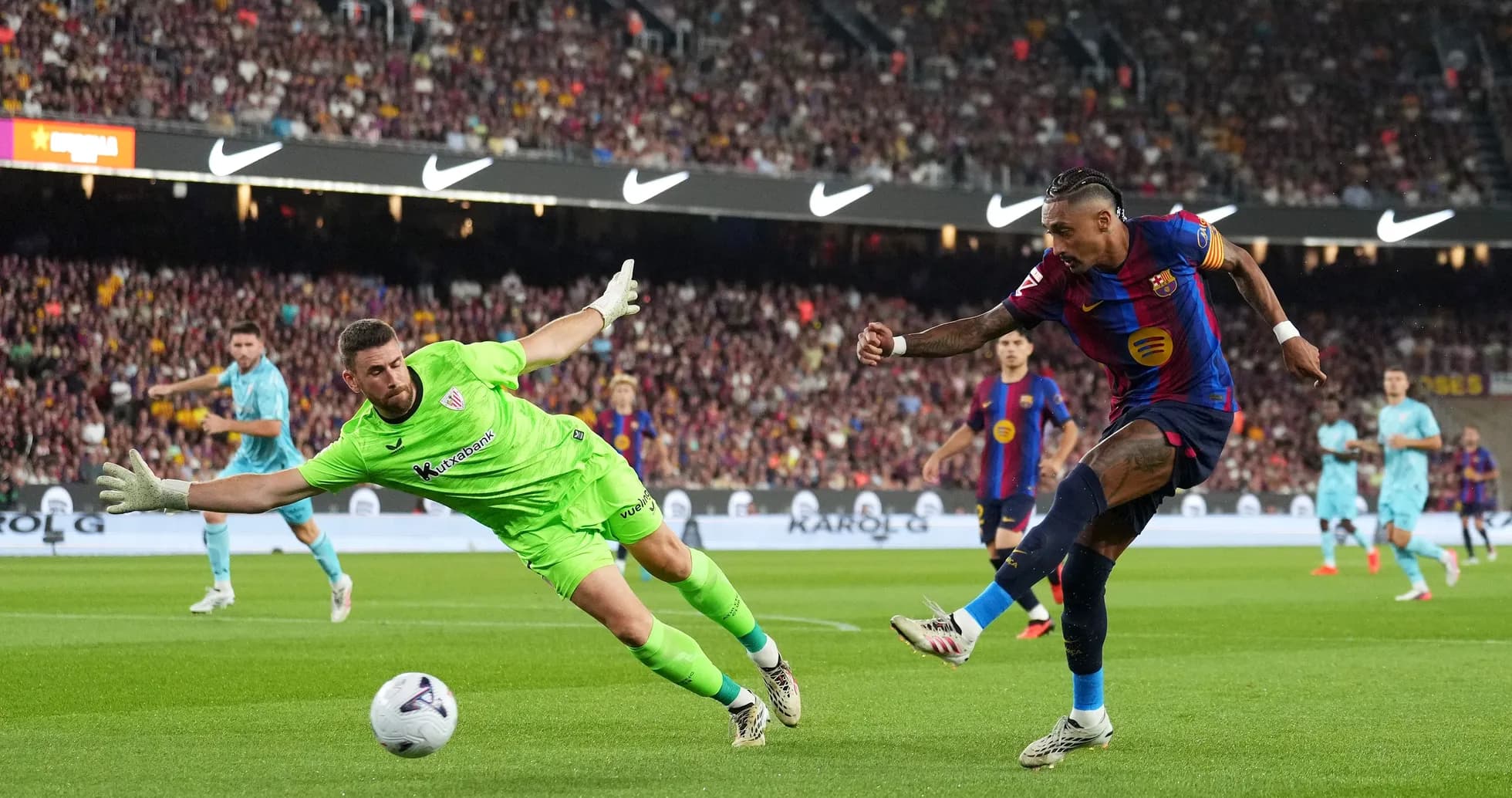 Barcelona player shooting as goalkeeper dives for ball Barcelona player shooting as goalkeeper dives for ball