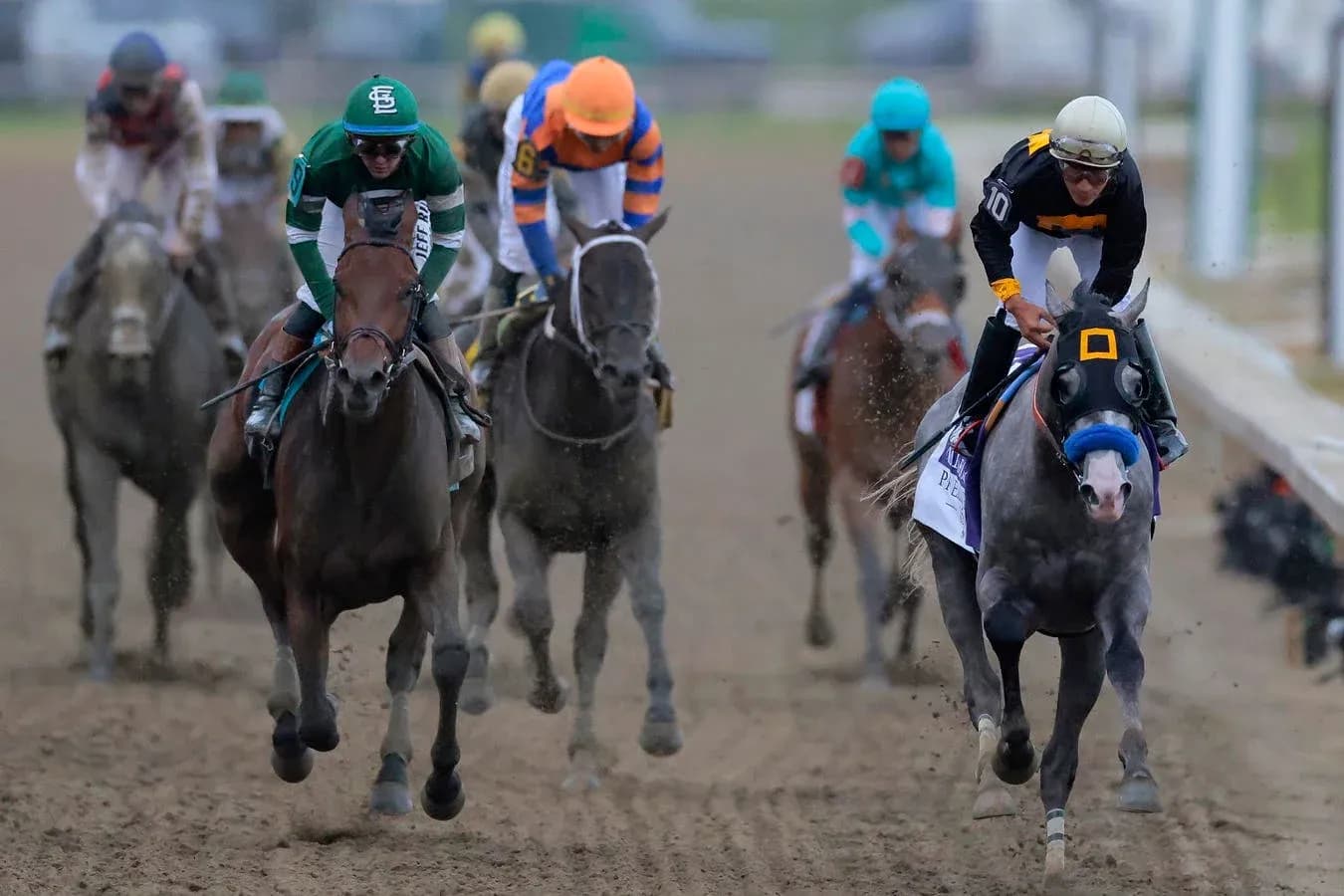 Jockeys racing horses on dirt track during competition Jockeys racing horses on dirt track during competition