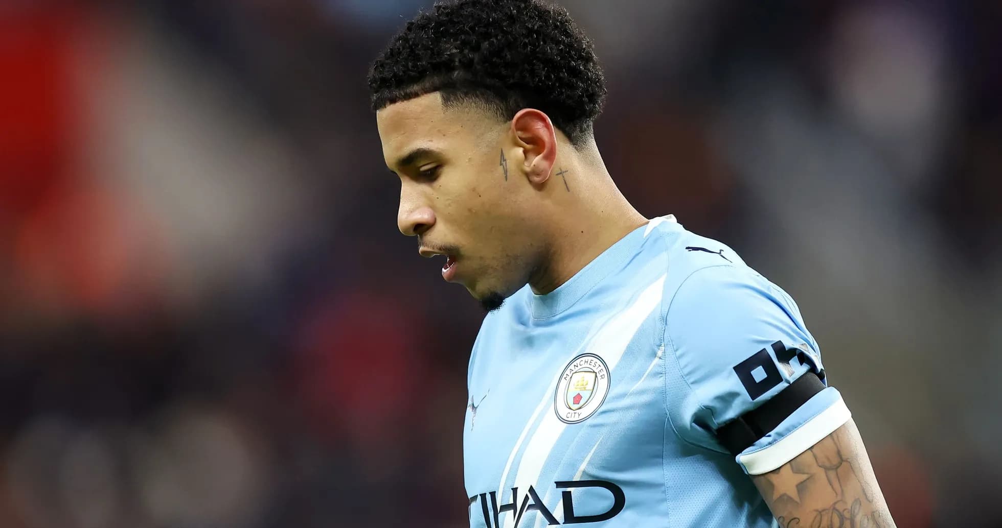 Futbolchi Manchester City formasida, pastga qarab turibdi Futbolchi Manchester City formasida, pastga qarab turibdi