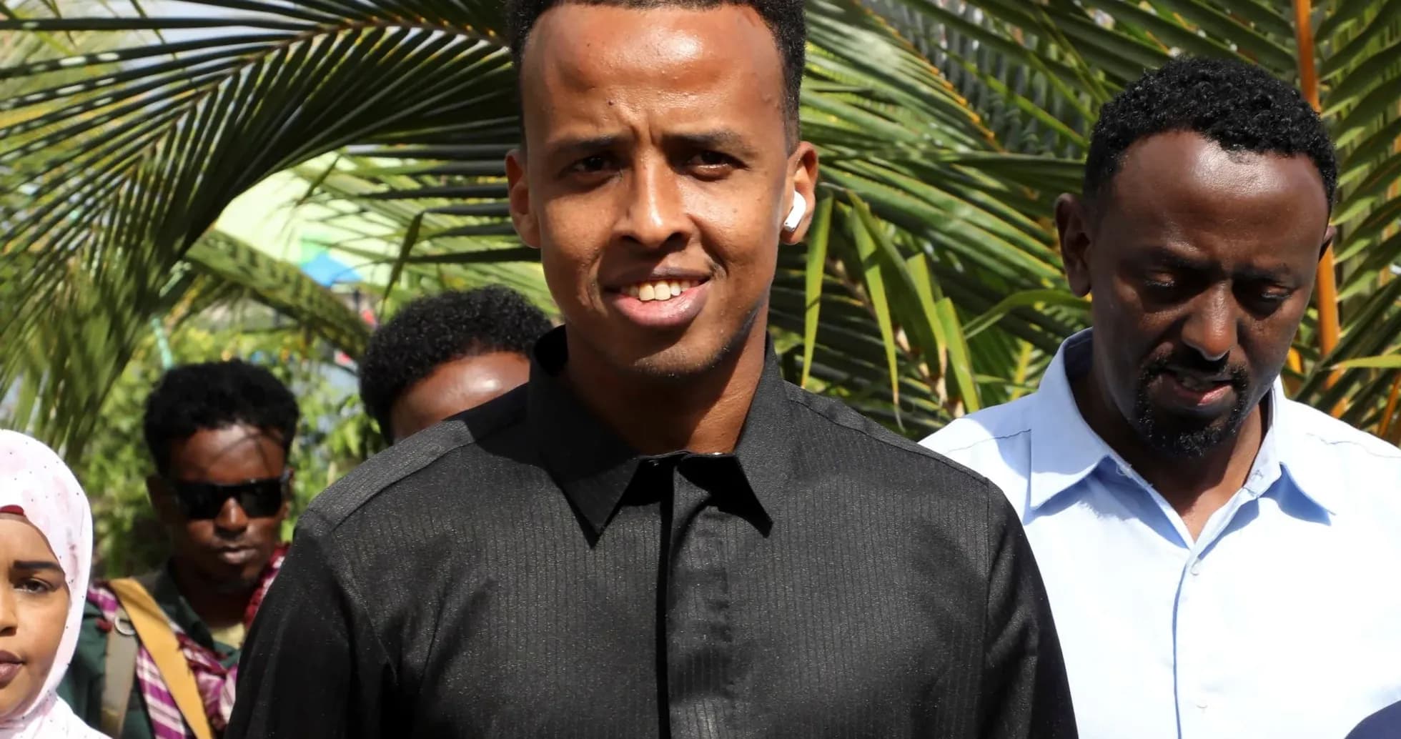 Young man smiling with group in background Young man smiling with group in background