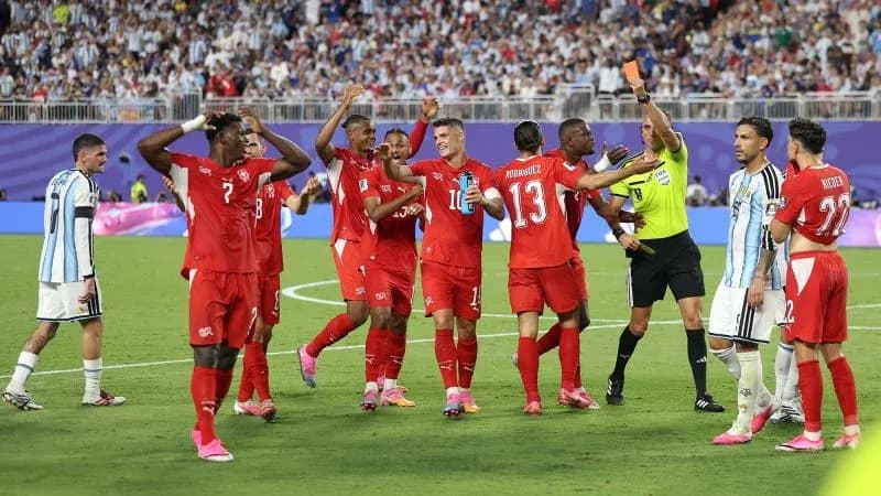 Swiss players celebrating while referee shows yellow card Swiss players celebrating while referee shows yellow card