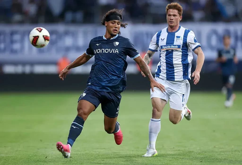 Player in blue jersey dribbling past opponent in white jersey Player in blue jersey dribbling past opponent in white jersey