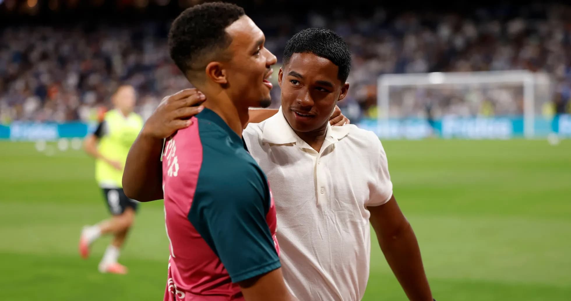 Two young men embracing on a football pitch Two young men embracing on a football pitch