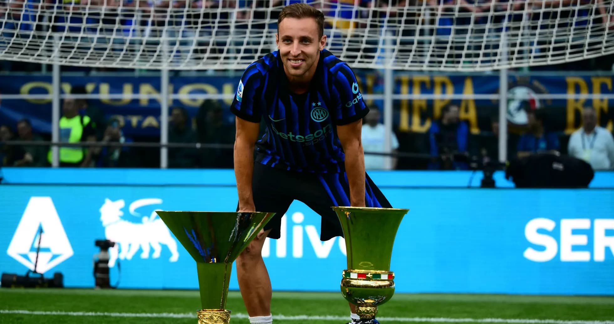 Futbolchi ikki kubok bilan maydonda turgan Futbolchi ikki kubok bilan maydonda turgan