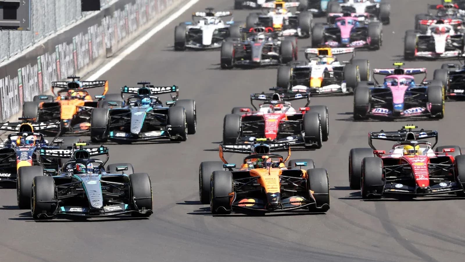 Formula 1 cars racing closely on the track Formula 1 cars racing closely on the track
