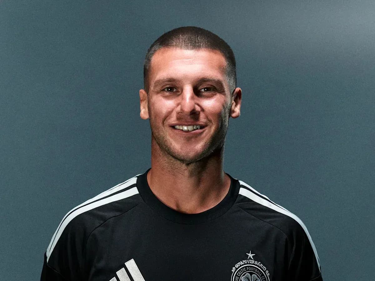 Futbolchi qora forma kiygan, tabassum qilmoqda Futbolchi qora forma kiygan, tabassum qilmoqda