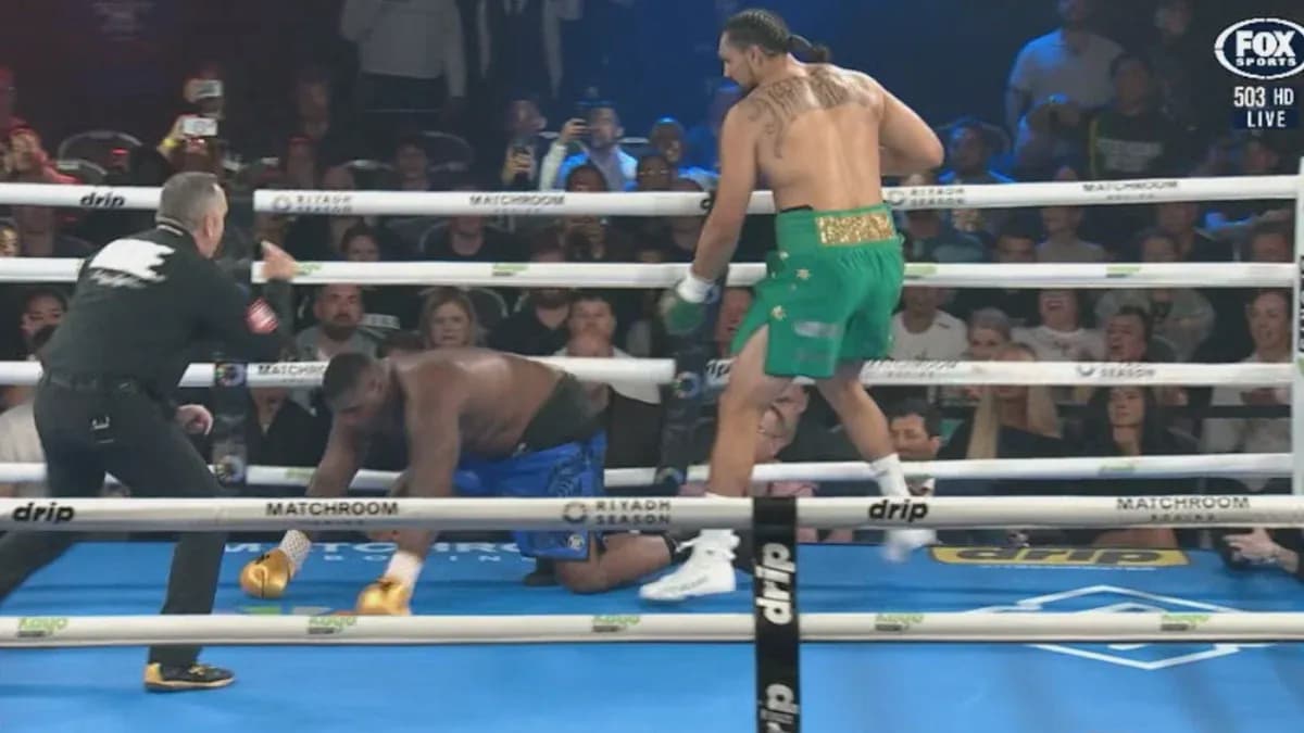Boxer in green celebrates as opponent kneels down Boxer in green celebrates as opponent kneels down