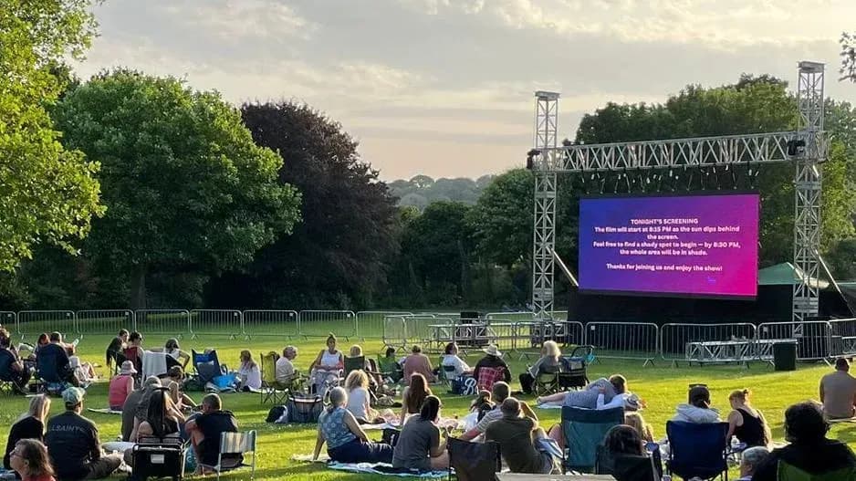 People watching outdoor movie screening in park People watching outdoor movie screening in park