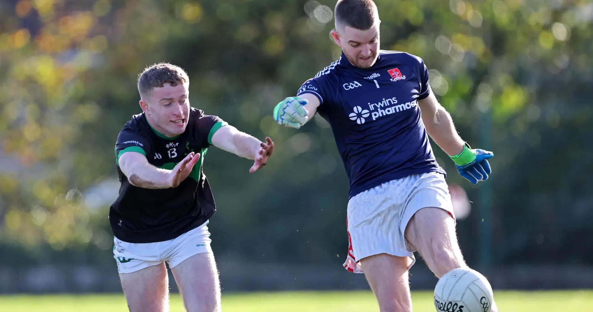 Player kicking ball while opponent reaches out Player kicking ball while opponent reaches out